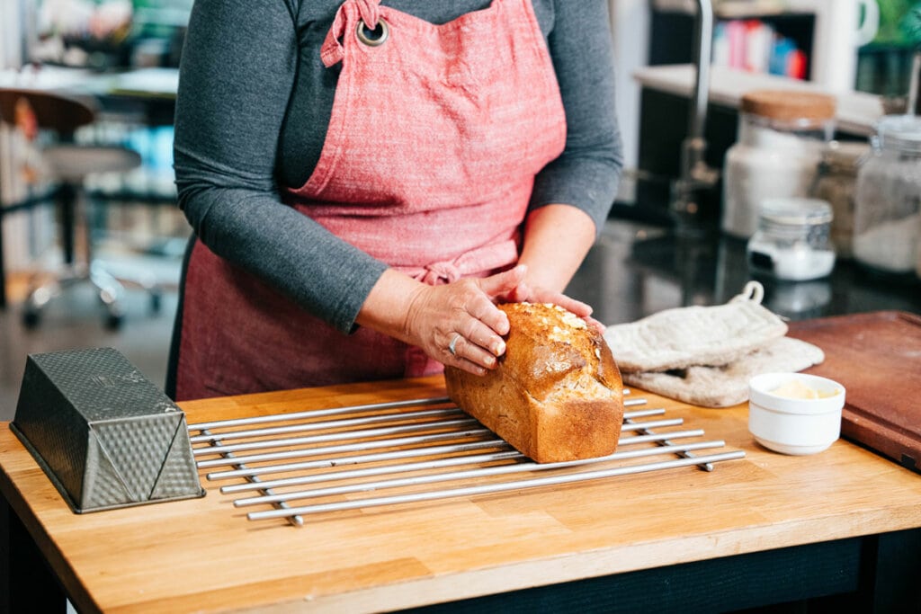 A woman holding a loaf of sourdough sandwich bread.