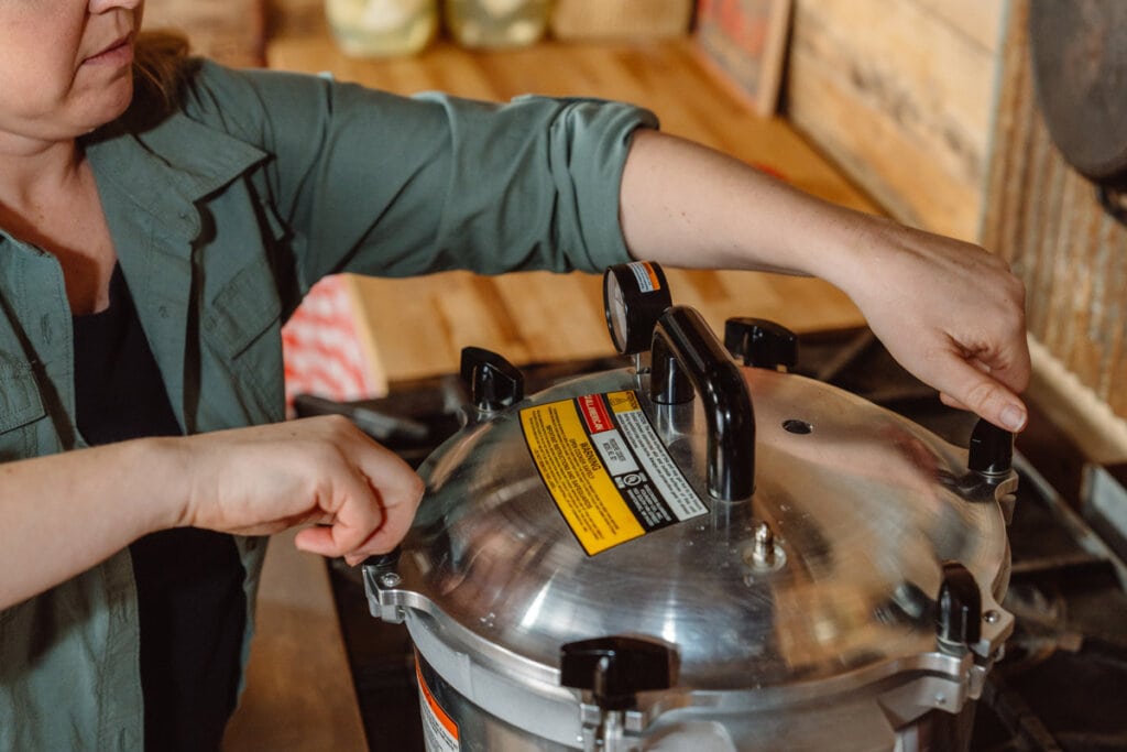 A woman tightening the lid of a pressure canner.