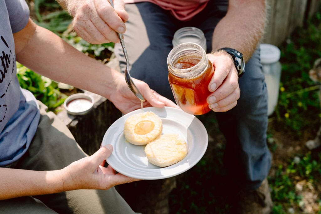 Raw honey being drizzled over fresh homemade biscuits outdoors