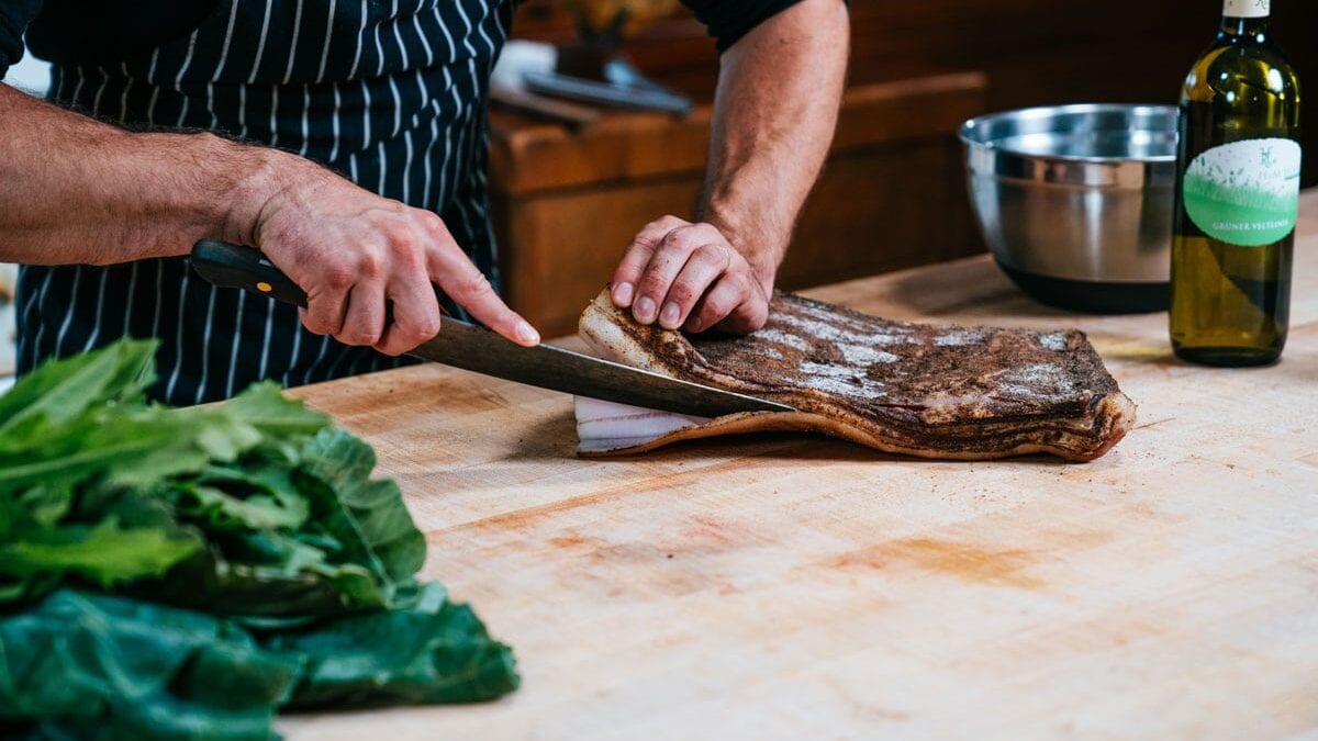 A man slicing cured bacon.