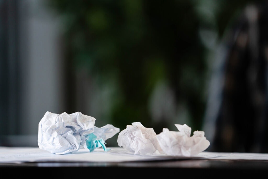 Crumpled paper drafts on a desk representing early planning and discarded ideas in homestead design